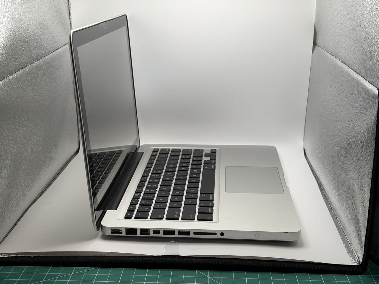 2010 unibody MacBook Pro open in a small photo lightbox