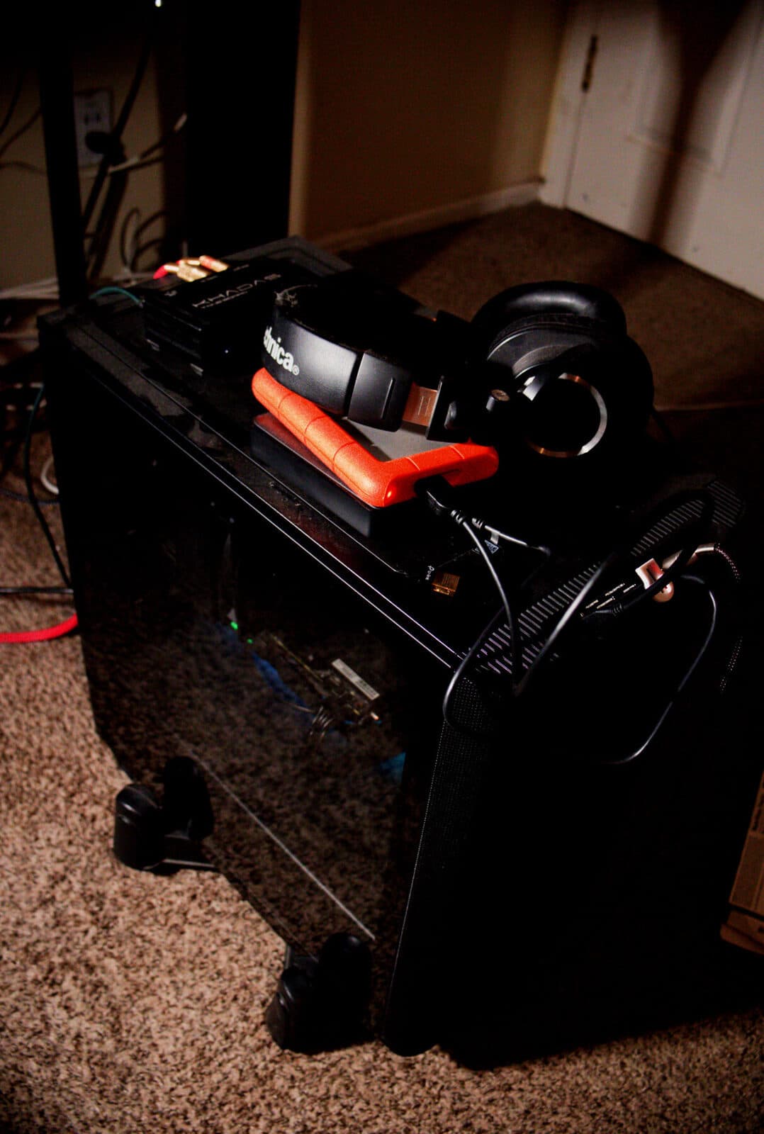 obsidian2, a black be quiet! tower PC, with a DAC, an orange backup drive and headphones resting on top